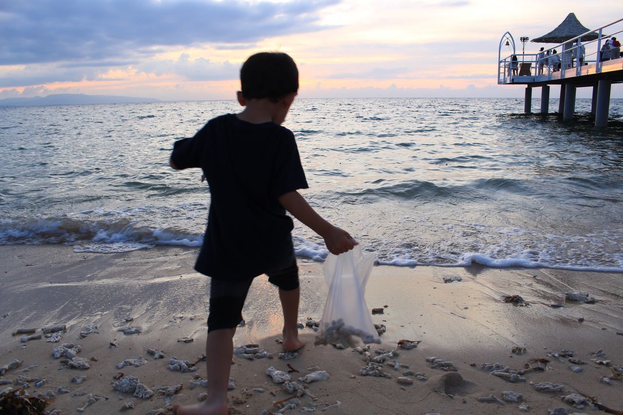 beach, shore, sand, sea, water, sunset, full length, horizon over water, standing, leisure activity, childhood, scenics, vacations, tranquil scene, sky, beauty in nature, wave, casual clothing, playing, cloud - sky, tranquility, nature, outdoors, enjoyment, person