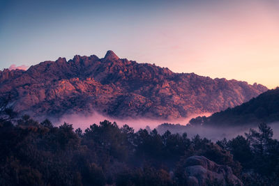 Scenic view of pedriza with mist diffusing between guadarrama mountain range and boulders with coniferous trees at sunrise in spain