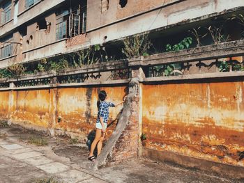 Rear view of woman walking by building