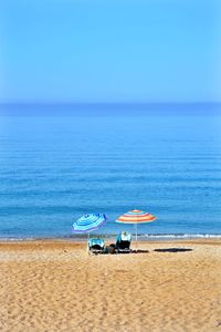 Deck chairs on beach against clear blue sky