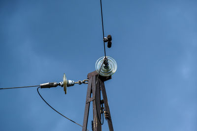 Low angle view of telephone pole against clear blue sky