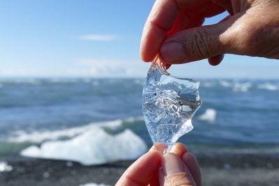 Cropped hand holding ice at beach