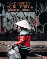 Rear view of man standing against graffiti