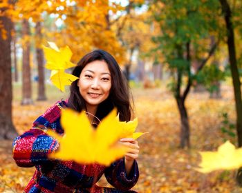 Portrait of woman throwing leaves during autumn