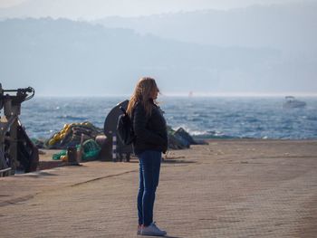 Side view of woman looking at sea while standing on promenade