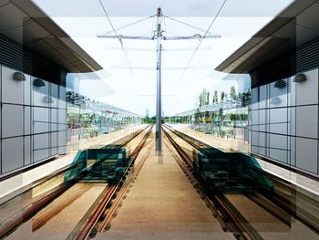 Railroad tracks amidst buildings against sky seen through glass