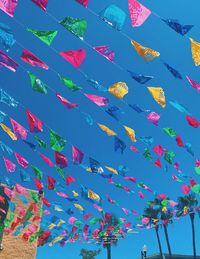 Low angle view of multi colored flags against clear blue sky