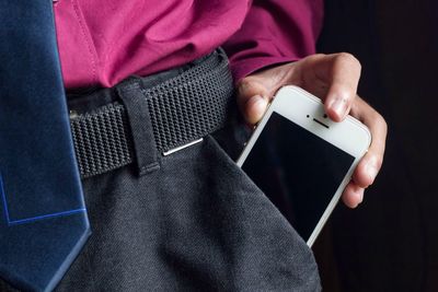 Midsection of man removing mobile phone from pocket