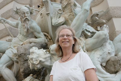 Close-up of smiling woman standing against statues