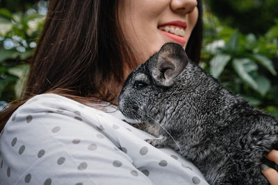 Close-up portrait of smiling woman holding chinchilla rodent with hand