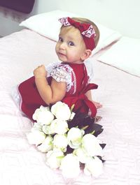Portrait of cute baby girl sitting on bed at home