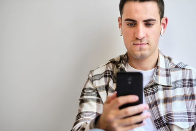 Young man with earphones looking at smartphone. chilling at home. copy space.