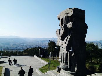 People walking on built structure against clear sky