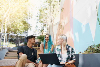 Smiling friends talking while sitting outdoors