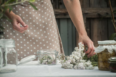 Midsection of woman holding flowers at table