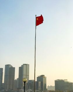 Red flag in city against clear sky