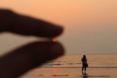 Rear view of woman on beach during sunset