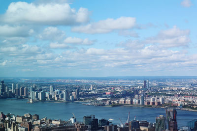 Aerial view of buildings in city against cloudy sky