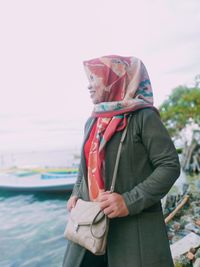 Midsection of woman holding umbrella while standing against sky