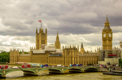 Bridge over river in city against cloudy sky