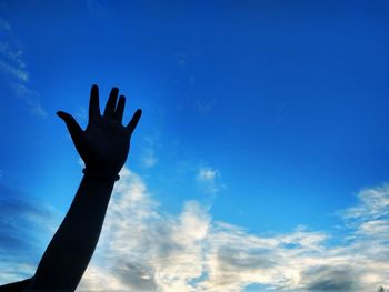 Cropped hand against sky