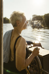 Senior woman steering houseboat on vacation