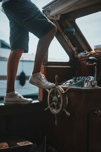 Low section of man standing on helm in boat