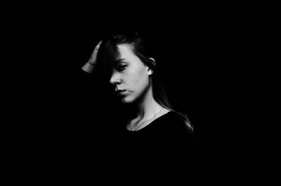 Portrait of young woman against black background