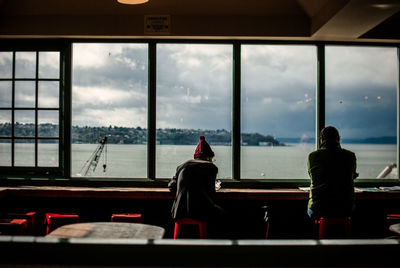 Rear view of men sitting by window at restaurant