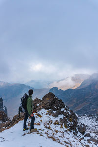 Rear view of man walking on mountain against sky