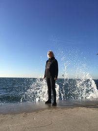 Full length of girl standing on beach against clear sky with wawes