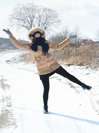 Portrait of young woman gesturing while standing at snow covered road