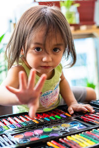 Portrait of cute girl gesturing while sitting by art and craft equipment on table