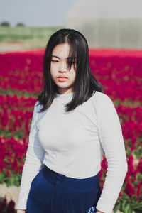 Portrait of beautiful woman standing by red flower