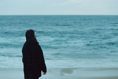 Woman standing at beach against sky