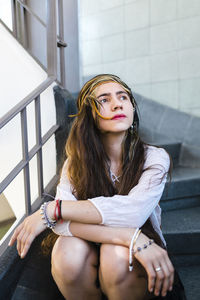 Hippie thoughtful young woman with long hair sitting on steps