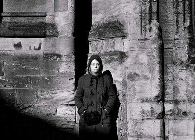 Portrait of young woman standing against window