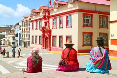 Plaza de armas square with group of local ladies in traditional andean clothing,  puno, peru