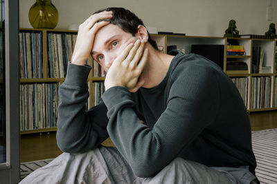 Depressed young man looking away while sitting at home