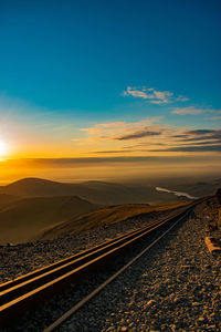 Scenic view of railroad tracks against sky during sunset