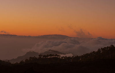 Scenic view of silhouette mountains against orange sky