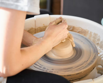 Midsection of potter making earthenware at pottery workshop