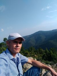 Mid adult man wearing cap on mountain against sky