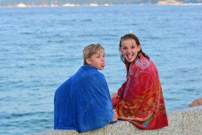 Two children on beach with towels and funny faces