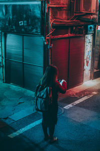 Rear view of woman walking on footpath at night