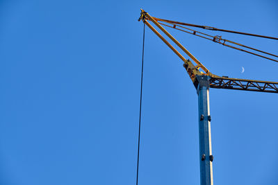 Low angle view of crane against clear blue sky