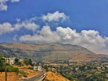 Road leading towards mountains against blue sky