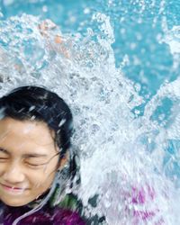 Close-up of smiling teenage girl swimming in pool