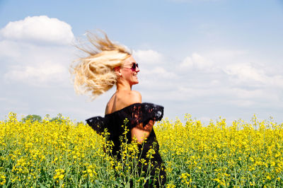 Smiling young woman tousled hair on oilseed rape field