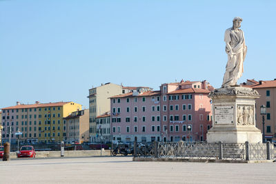 Statue against buildings in city against clear sky